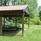Covered pavilion / picnic shelter beside grassy area and pond — useful image of event/amenity space and adjacent water on the property (file appears on the campground page).
