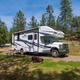 Close view of an RV parked at a furnished RV site (picnic table, fire ring) — clear depiction of typical RV accommodations (RV Sites page).