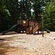 Children's playground surrounded with wood chips and nestled in the forest.