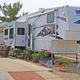 Photograph of an RV parked at a paved site with outdoor furnishings and landscaping — useful to show typical RV pitch style at this resort (from the resort gallery).