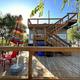 Alternate bright-angle view of the same deck/patio structure with chairs, umbrella and stair access — useful to show outdoor recreation and seating areas from the park homepage (The Buzz RV Park, https://www.thebuzzrv.com/).