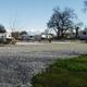 Panoramic header image showing multiple RVs on gravel pads beside water and trees — good wide view of the park’s campsite area (site header background).