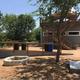Shows an outdoor pavilion/deck area with seating and a small stone firepit — clear on-site amenity photographed on the park homepage (The Buzz RV Park, https://www.thebuzzrv.com/). Good representation of guest common space.