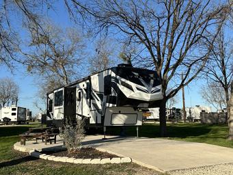 Close-up of a single RV on a concrete pad with picnic table and landscaped edging — good detailed view of an individual RV site and site furnishings (from the home page imagery).