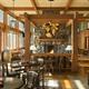 A cozy restaurant with wooden furniture, a stone fireplace, and large windows that let in natural light, creating a warm atmosphere.