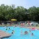 Photograph of the on‑site swimming pool with lounge chairs and patrons; clearly depicts a campground pool and is from the resort’s amenities page.