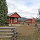 Paddy Flat Guard Station Cabin East at a medium distance with rustic fence and trees. Barn in the background.