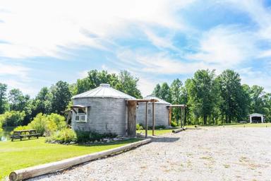 Pair of round/yurt-style cabins near gravel roadway and picnic area — shows alternative cabin types and site layout (Old Goat/other cabins page background).