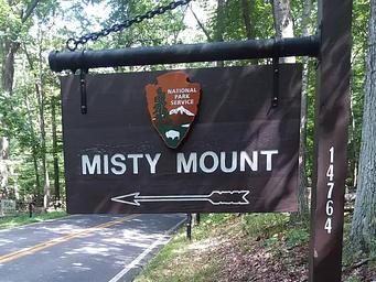 Outdoor wooden sign labeled "Misty Mount" with an arrow symbol.