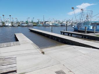 View of boat ramps and multiple commercial fishing boats at the marina docks — illustrates marina slip/launch facilities listed on the site.