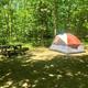 Clear on-site campsite photo showing a tent pitch, picnic table and wooded surroundings — matches the homepage/gallery on the campground website (page: campmv.com). Good representation of tent camping areas.