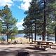 Beautiful view of the lake with a picnic table, fire ring and trees in the background