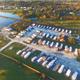 Aerial overview showing the campground layout with rows of RV sites, access roads, a central building and adjacent lake — clearly depicts property grounds and site arrangement (homepage gallery).