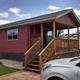 Exterior of a covered-porch cabin on-site showing cabin style, deck and adjacent RV — good for rental accommodation listing (rental unit page).