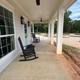 A porch with rocking chairs and a ceiling fan
