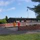 Ground-level photo of the main office/clubhouse entrance, flags and parking — fits the property landing/contact page context for Deer Meadow Campground.