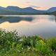 Wide scenic lake view with mountains and shoreline — appears on the property homepage/photo gallery (used as a hero/background image), good for showing onsite natural scenery and nearby water feature.