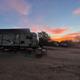 Wide dusk view of an RV parked on gravel with other vehicles and campground trees visible — good overall site/lot perspective. Image is from the property homepage (Granberry Gardens LLC).
