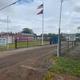 a dirt road leading to a fenced in area with a flag on a pole .
