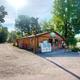 Front office/general store building beside the pond and entrance road — shows on‑site services and orientation within the campground.