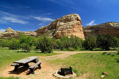 A picnic table at a campsite in Echo Park Campground with Rock Formations in the background