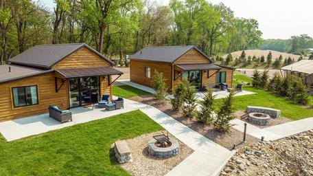 Raised-angle shot of multiple cabin units with patios and fire rings along the shoreline — useful overview of cabin accommodations and landscaping near the lake.
