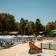 Large view of the campground’s main pool and surrounding lounge chairs, water play features and nearby trees — clearly on-site and pulled from the property homepage (site social image).