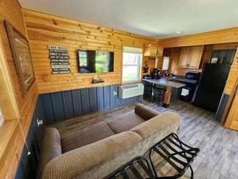 Cottage interior: living area and kitchenette in a wood-paneled cottage — demonstrates on-site cabin accommodation and amenities (from property rates/amenities gallery).