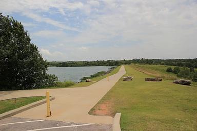 A view of the dam area and trail on Veteran's Lake under a blue sky with cirrus clouds