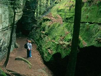 Hikers look at the high rock walls at the Ledges
