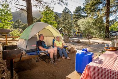Tent campsite photo with camp chairs, tent, picnic table and nearby campground features — good representation of tent camping options and on-site atmosphere.