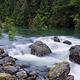 River flowing over rocks with trees in the background.