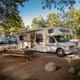 Clear photo of an individual RV campsite with picnic table, grill and surrounding trees — useful detail of RV site amenities and setting on the property page.