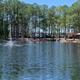 Daytime lake view with fountain, gazebo and RVs visible across the water — clear scenic overview of on-site pond and surrounding campsites (homepage imagery).