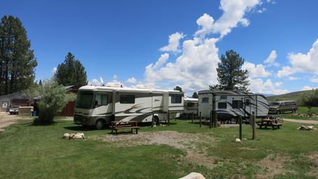 RV hook-ups and parking area: wide daylight shot showing multiple RVs on grassy pads with picnic tables and hookups (clearly depicts campground RV facilities; from 'General 2' page).