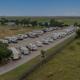 Aerial/drone-style overview showing a long row of RVs, paved drives and surrounding pasture — clear property overview matching the site's home page background image.