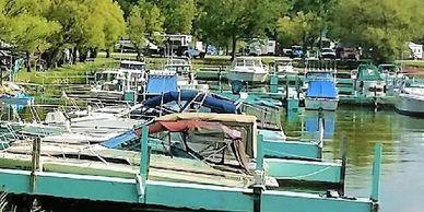 A calm marina filled with various docked boats and lush green trees.