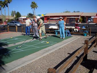 Shuffleboard courts with players, RVs and park buildings visible in background — depicts on-site activities and layout (source page: Rates).