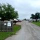 Driveway/entrance view with fencing, sign and lined RVs visible — useful for showing access and typical site layout; sourced from the Park Information page.