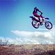 Rear view of motorcyclist jumping a dune.