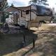 Close view of an RV at a campsite with awning, chairs and outdoor setup — good for illustrating typical RV pitch space and site features (from the campsite page images).