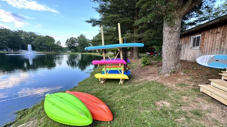 Lakeside equipment and shoreline scene with stacked kayaks and paddleboards next to a small boathouse — illustrates on-site lake recreation and waterfront facilities (visible in site gallery).