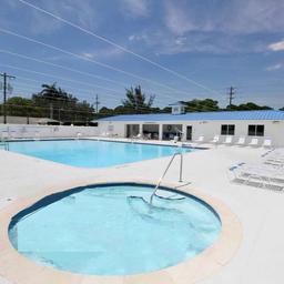Ground-level pool and spa photo showing amenities, pool deck and clubhouse building — complements aerial pool image (site gallery ‘pool-and-spa pic-2025’).