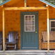 Front view of a wooden cabin with porch chairs; from the site's 'Cabin' ways-to-stay section — depicts on-site cabin accommodation.