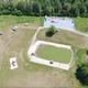 Top-down drone image focused on the play/pond and adjacent grounds with walking areas and playground visible — helpful for showing the central recreational feature.