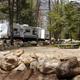 Gravel campsite with rock border and a trailer in the background — demonstrates site layout and typical pitch separation. Appears in the site’s home page gallery (Slide-Rocks).