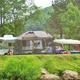 Riverside campsite with tent, trailer and lawn area adjacent to rocks/riverbank — clearly shows tent/RV camping options (from the site’s Rates & Reservation gallery).