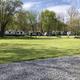 Grassy field with lined RVs and picnic tables — image on the RV Camping page showing the level pads/long-term sites and surrounding lawn area, useful for illustrating site layout.