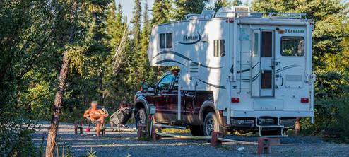 Close view of an RV parked at a gravel site with picnic table and hookups visible — good depiction of the RV pitches and campsite setup; originates from the site gallery.