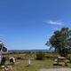 Clear photo of an RV/trailer pitch with picnic table, campsite utilities/hookup box and sea view — shows an actual campsite on the property and matches the page context highlighting waterfront sites.